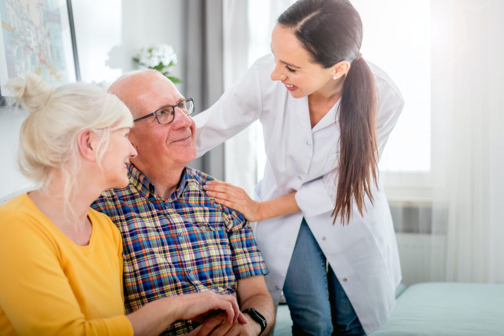 Smiling nurse talking with senior couple during home visit